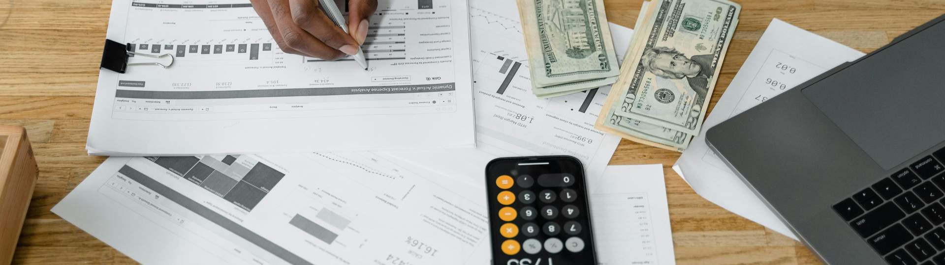 Desk with paperwork layed out with a calculator and laptop