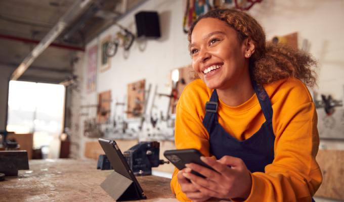 Small business owner leaning on her store counter smiling