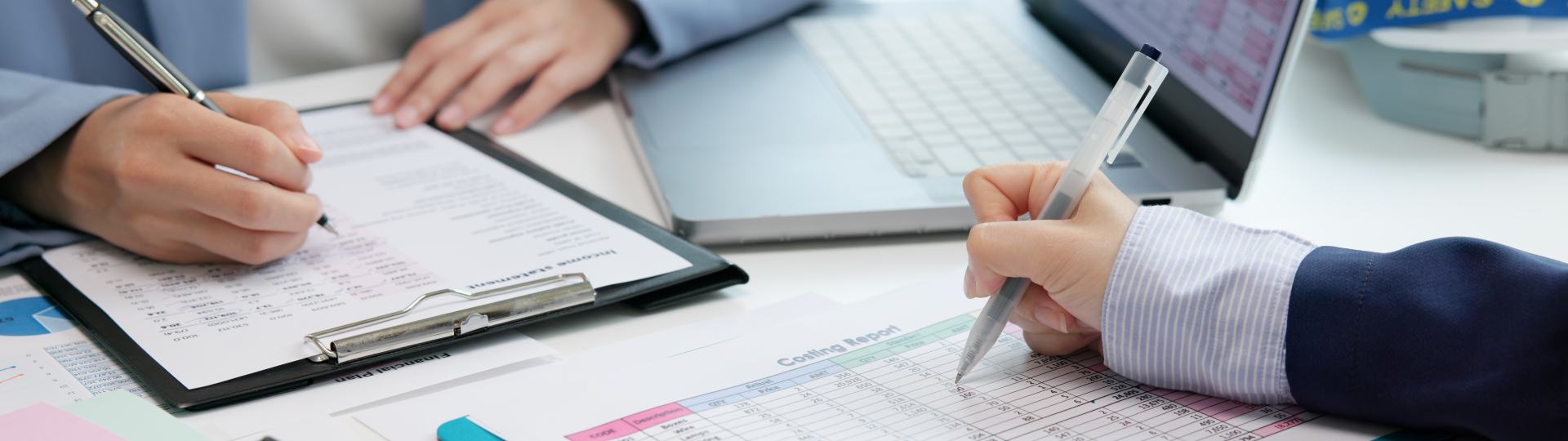 Two people filling out paper work at a desk