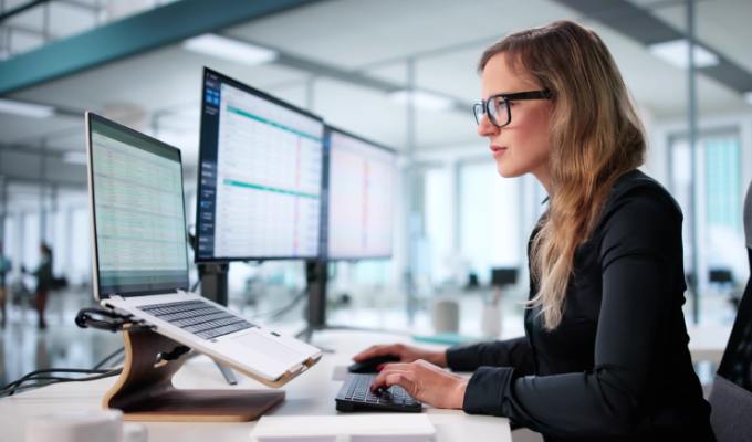 Woman sitting in corporate office looking at finances on her computer
