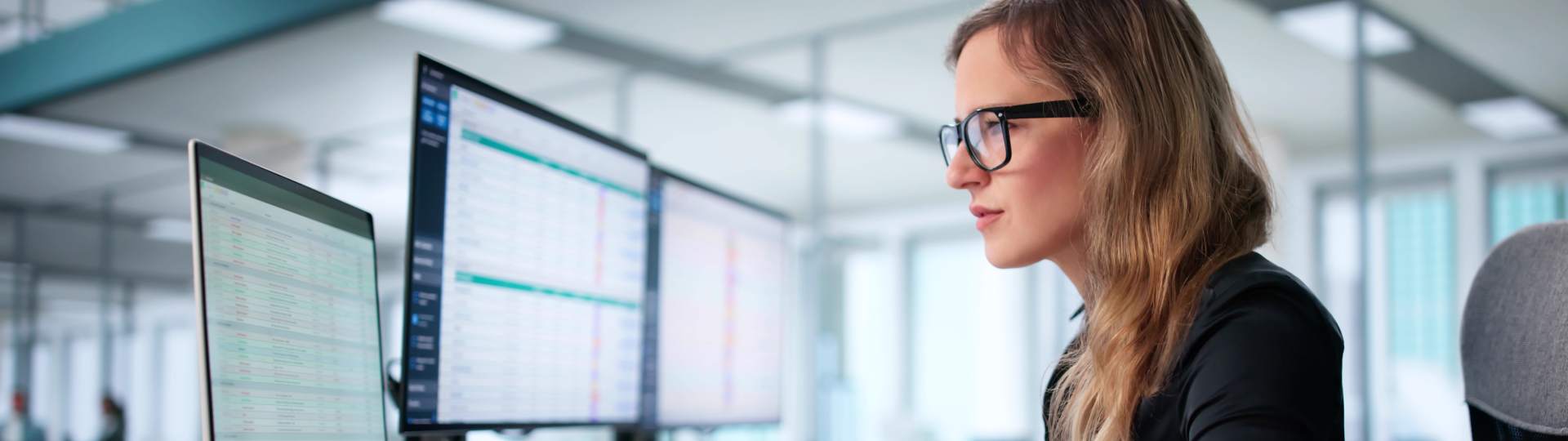 Woman sitting in corporate office looking at finances on her computer
