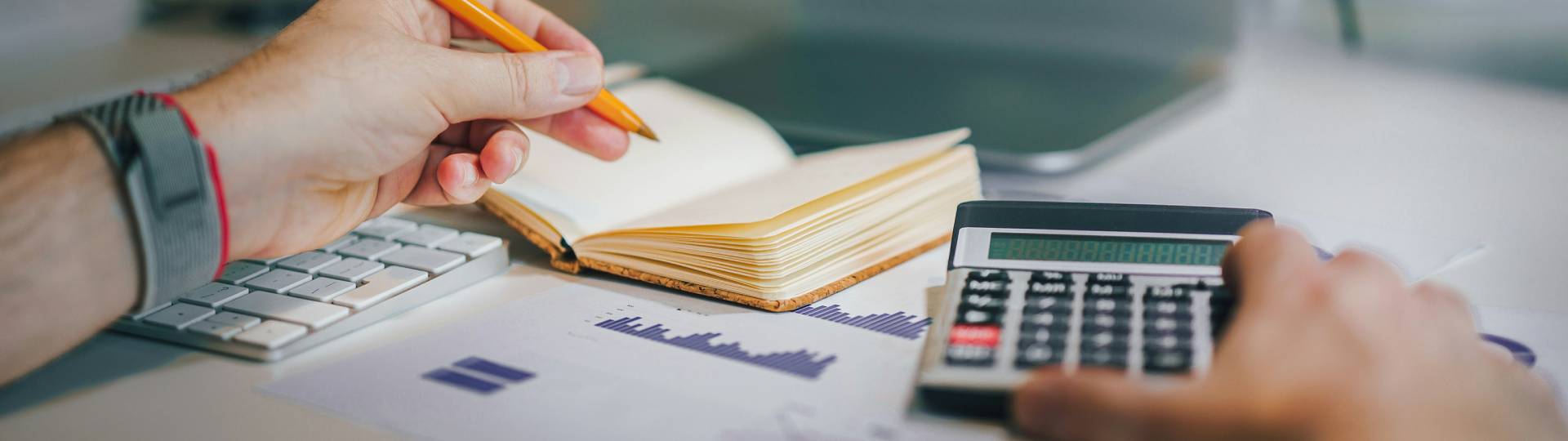Man using a calculator looking at paperwork and making notes