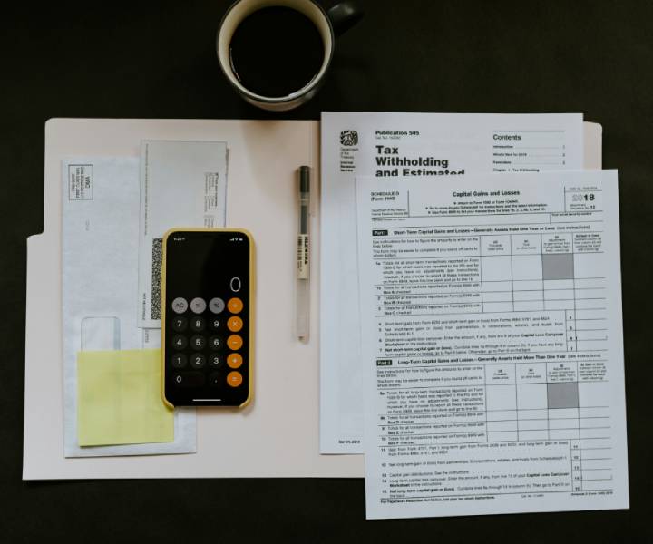 An open folder on a desk with various tax forms and a calculator