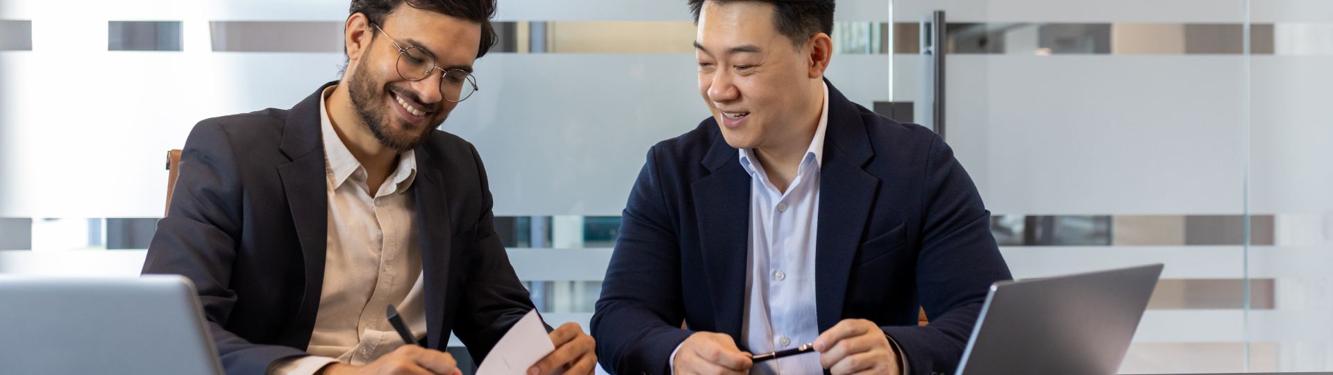 Two business partners signing papers smiling