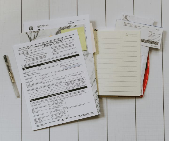 An open folder on a desk with various tax forms inside